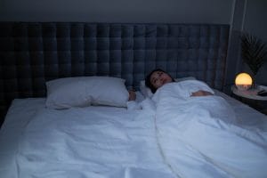 Yatakta gözleri açık, uyuyamayan ve telefona bakan kadın