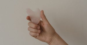 Gua Sha ve Yüz Masajı: Ödem ve Kontur İçin İşe Yarar mı? Yüzüne gua sha taşıyla elmacık kemiği boyunca masaj yapan kişi