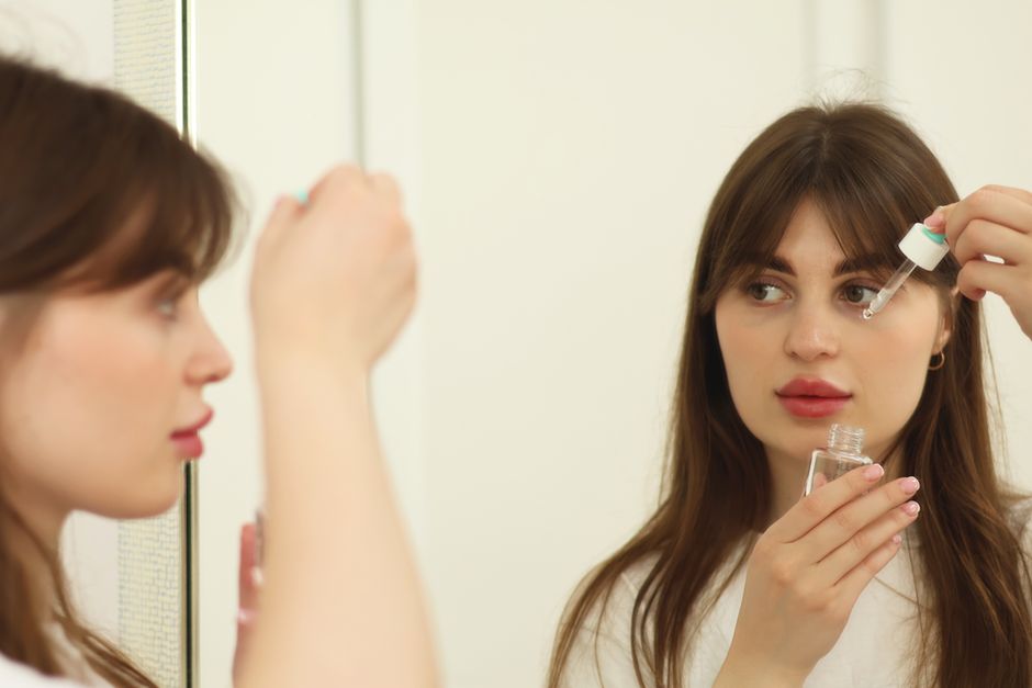 Aynada kaşına serum uygulayan bir kişi