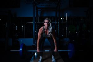 Spor salonunda ağırlık kaldıran olgun kadın